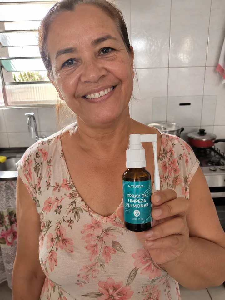 Cliente na cozinha de casa segurando o frasco do Naturva™ Spray de Limpeza Pulmonar