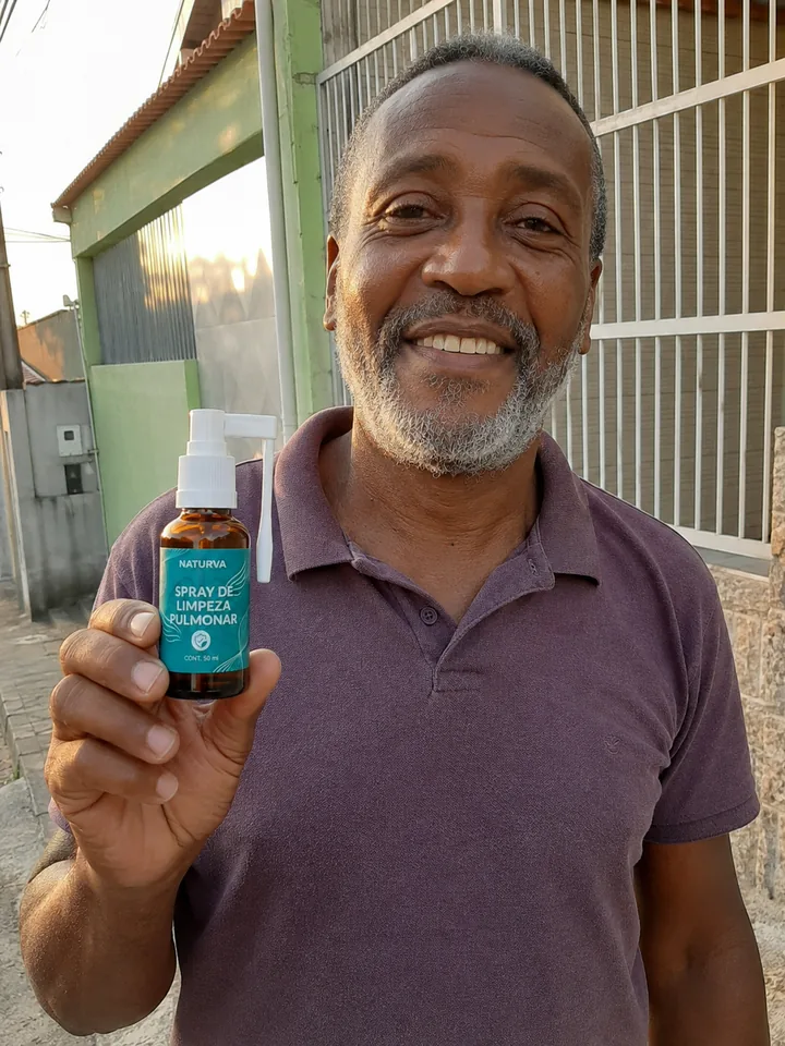 Cliente em frente de casa segurando o frasco do Naturva™ Spray de Limpeza Pulmonar